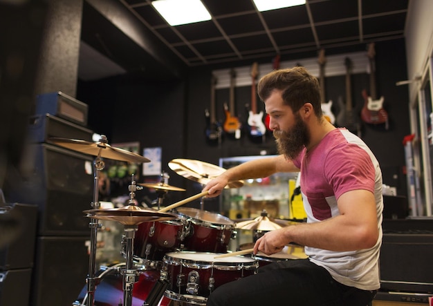 music, sale, people, musical instruments and entertainment concept - male musician playing cymbals at music store