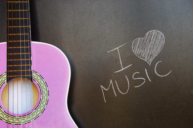 Music school for children with purple guitar closeup on blackboard background