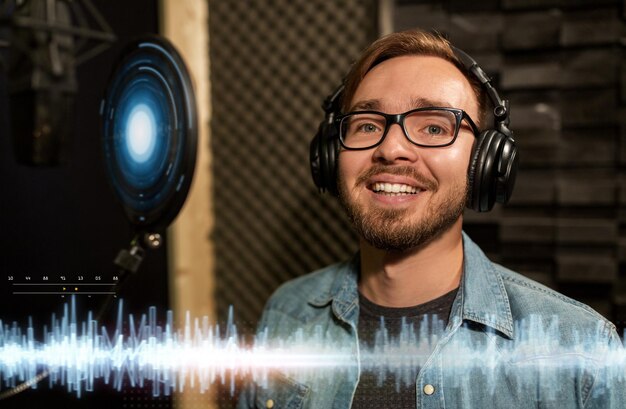 Foto persone del mondo dello spettacolo musicale e tecnologia concetto cantante maschio con cuffie e microfono che canta una canzone in uno studio di registrazione del suono