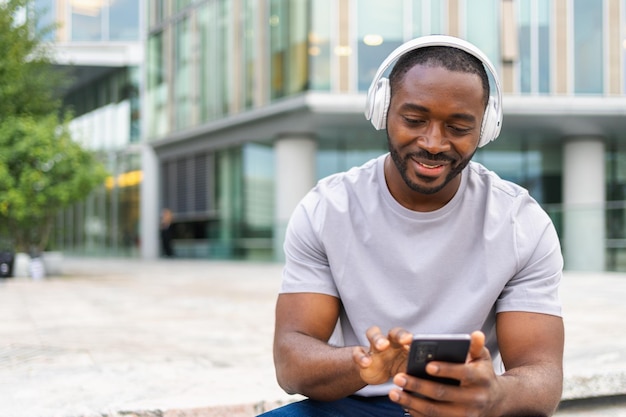 Foto concept musicale buon inizio di giornata felice uomo afroamericano ascoltando il successo moderno per strada in città