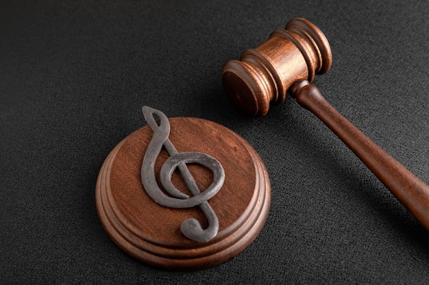 Music symbol treble clef and judge gavel on black background. Music piracy and copyright infringement.