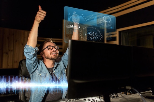 音楽・テクノロジー・ジェスチャー・アンド・ピープル・コンセプト 音声録音スタジオのミキシング・コンソールで幸せな男 親指を上げる