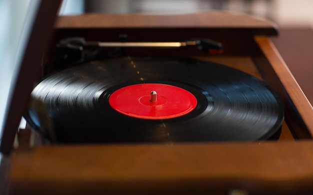 music, technology and object concept - close up of vintage record player with vinyl disc