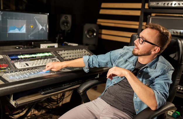 Photo music technology people and equipment concept man at mixing console with computer monitors in sound recording studio