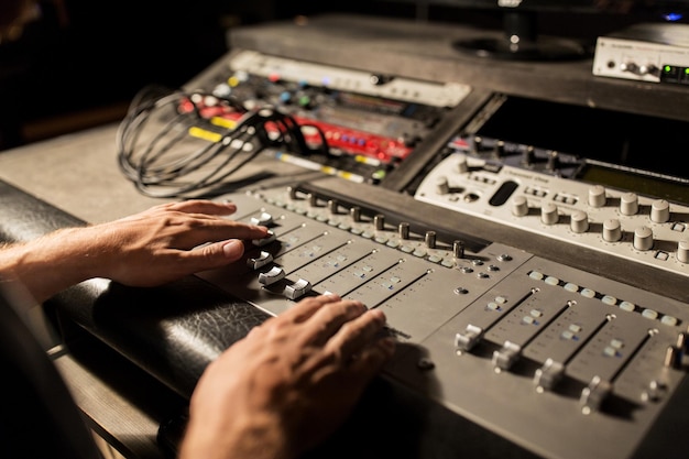 Photo music, technology, people and equipment concept - man using mixing console in sound recording studio