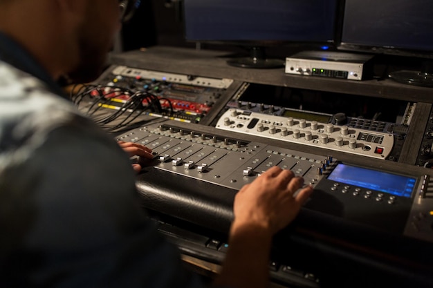 음악, 기술, 사람 및 장비 개념 - 사운드 녹음 스튜디오에서 싱 콘솔을 사용하는 사람