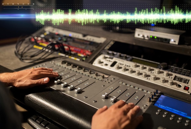music technology people and equipment concept sound engineer hands using mixing console at recording studio
