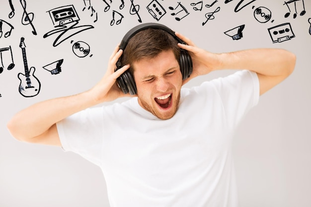 music and technology - young man with headphones listening loud music