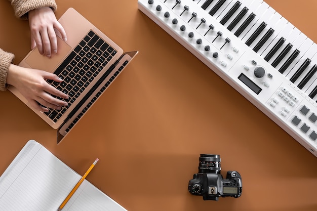 Photo musical background with musical keys, laptop and female hands, top view.