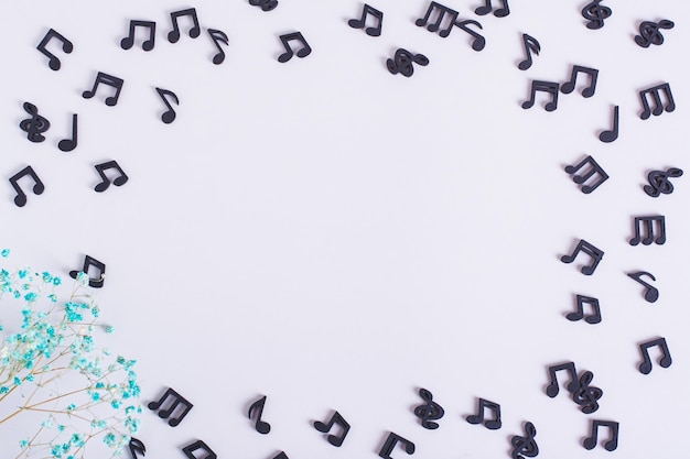 Photo musical concept frame made of black notes and dried flowers on a light background