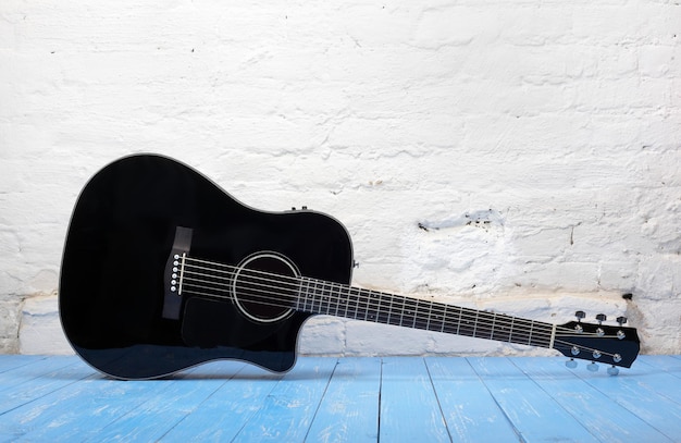 Musical instrument Black acoustic guitar brick background