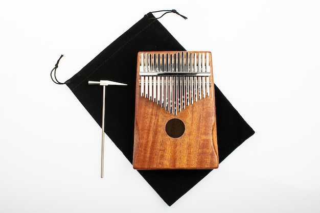 Strumento musicale kalimba con un piccolo martello di metallo per l'accordatura su sfondo bianco