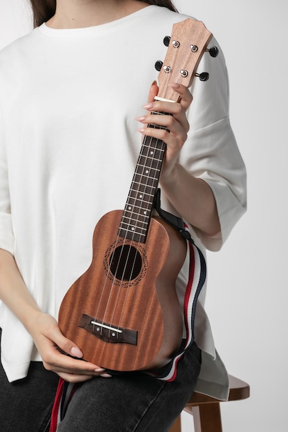 Strumento musicale ukulele nella mano di una donna su sfondo bianco