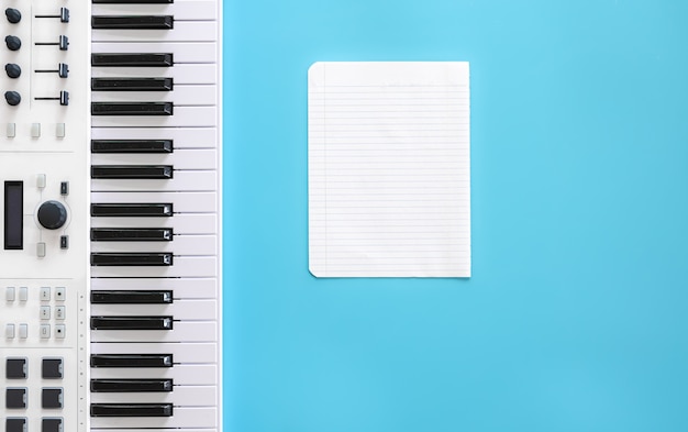 Musical keys and blank paper on a blue background, the concept of writing music, musical creativity.