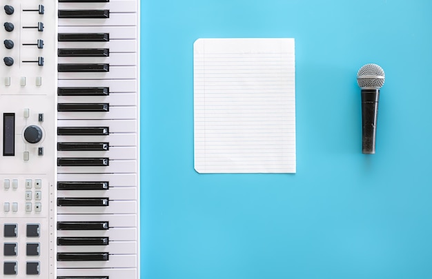 Musical keys microphone and blank paper on a blue background