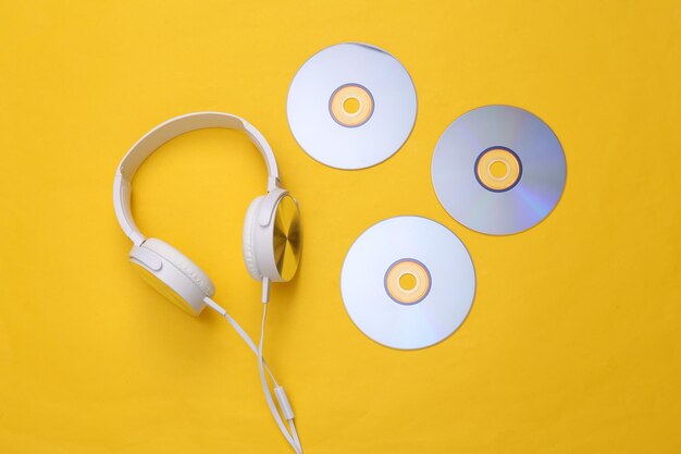 musical layout headphones and cd on yellow background top view flat lay