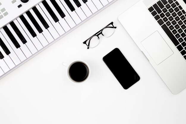 Musical still life with a smartphone a cup of coffee musical keys and a laptop on a white background