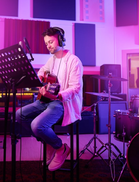 Foto musicista cuffie o chitarra in studio al neon produzione di registrazione o esibizione su etichetta radiofonica o concerto di band artista chitarrista o uomo che suona su strumenti a corda nella pratica della luce notturna