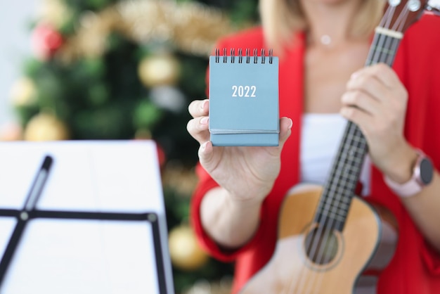 Il musicista tiene il calendario per e la chitarra sullo sfondo dell'educazione musicale dell'albero di capodanno