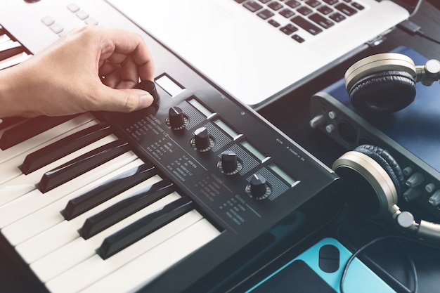Photo musician is adjusting sound on synthesizer keyboard