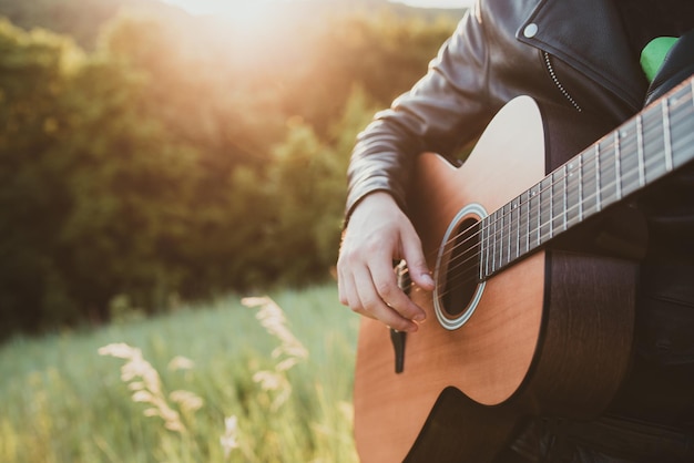 Uomo del musicista che suona la chitarra al primo piano del tramonto