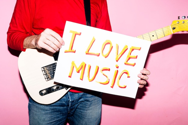 Uomo musicista con chitarra e cartello che dice che amo la musica