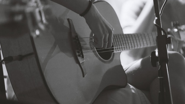 Musicista in night club - il chitarrista suona la chitarra acustica blues, estremamente ravvicinato - bianco e nero, teleobiettivo