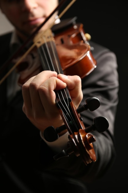 Musician play violin on black background close up