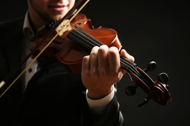 Il musicista suona il violino su sfondo nero da vicino