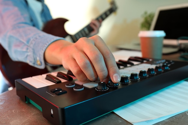 Photo musician playing on electric guitar and midi keyboard, close up