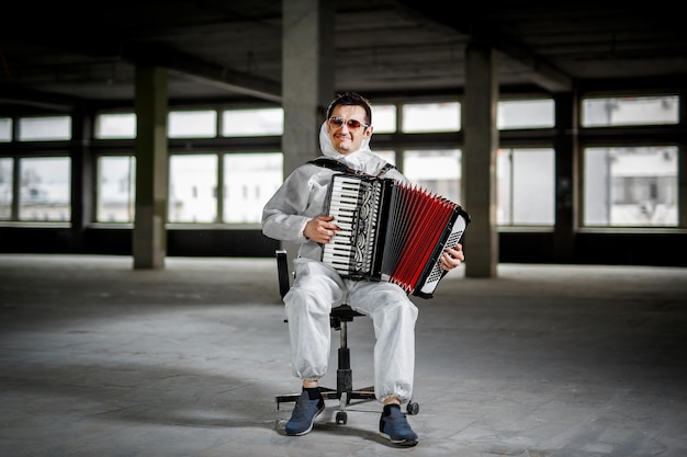 The musician playing the harmonica, accordion in the hall with columns