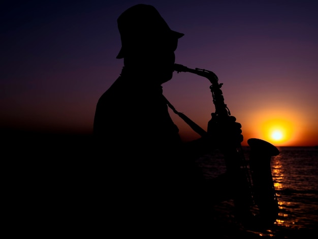 A musician playing the saxophone at sunset