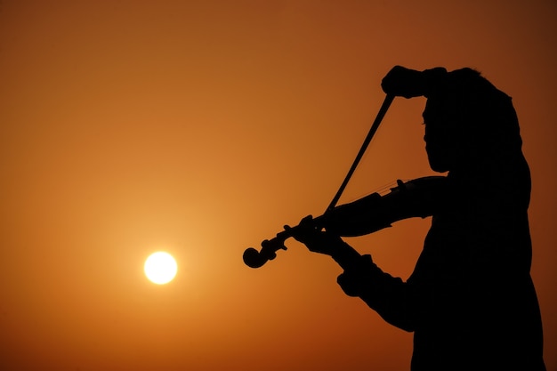 바이올린을 연주하는 음악가. 음악과 음악적 톤 개념입니다. 남자 음악가의 실루엣 이미지