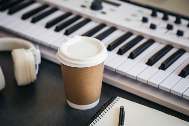 Foto tavolo da lavoro per musicisti con coppa di carta e tastiera bianca per pianoforte