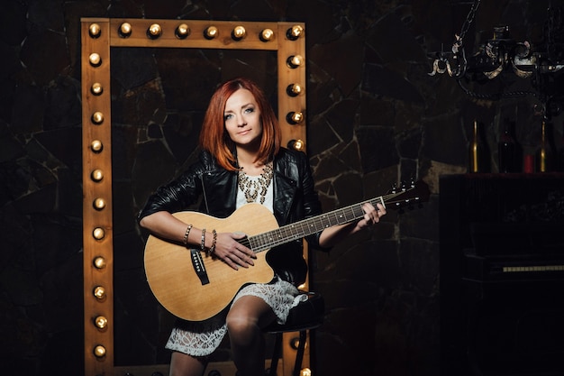 Musician young woman with red hair with an acoustic guitar