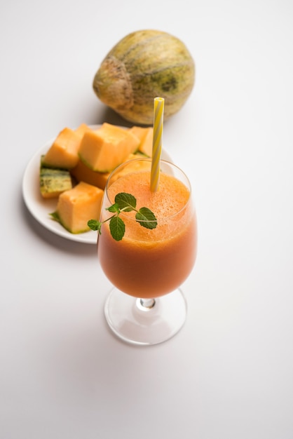 Musk melon juice with slice, also known as Kharbuj or kharbuja fruit extract, served in a glass with mint. selective focus