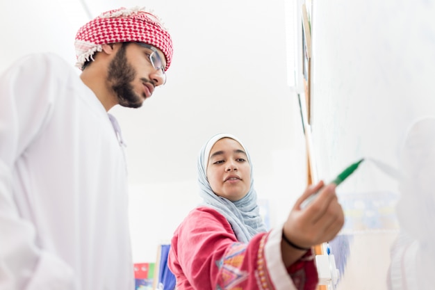 Muslim arab students solving a math question on the whiteboard