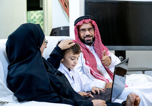 Muslim arabic boy showing his parents his laptop and his work on it