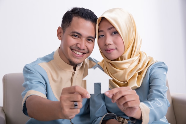 Muslim asian couple holding home sign