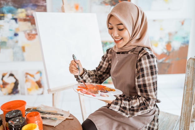 キャンバスに描くイスラム教徒のアジアの女性アーティスト