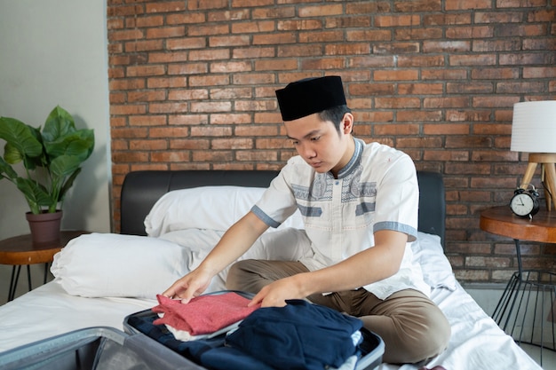 Muslim asian male preparing and packing clothes