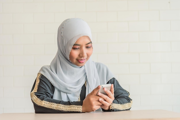 La donna asiatica musulmana usa lo smartphone controlla l'e-mail ragazza asiatica guarda i social media dall'aspetto mobile