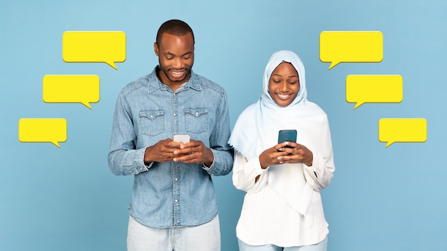 Muslim black couple using cellphones texting among message\
icons studio