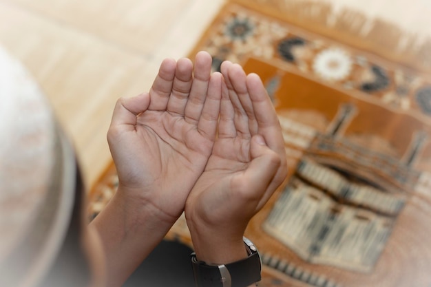 Фото Мальчик-мусульманин в платке молится ему, молясь емувид сверху на молодого мальчика-мусульманина, молящегося дуа