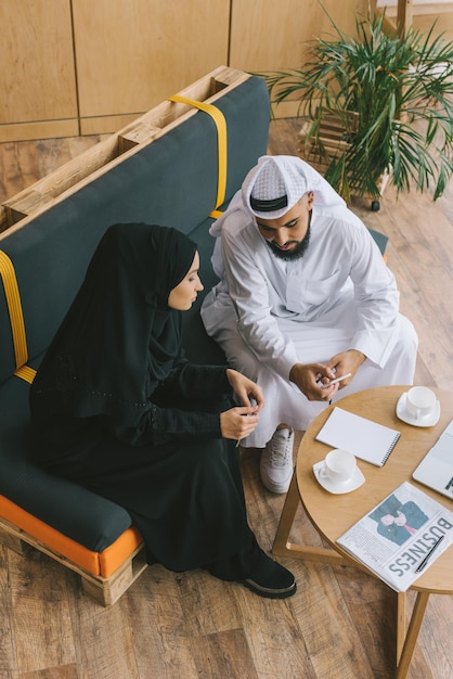 Muslim business partners looking at phone in office lobby