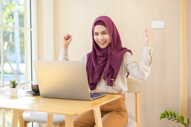 커피 숍에서 그녀의 노트북을 사용하는 hijab를 착용하는 이슬람 비즈니스 여성