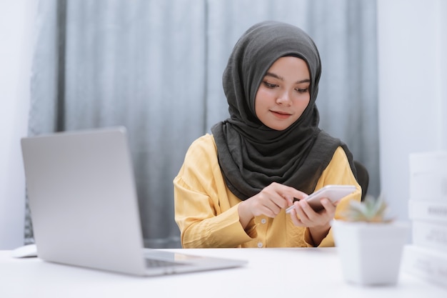 노트북과 스마트 폰으로 집에서 일하는 이슬람 사업가