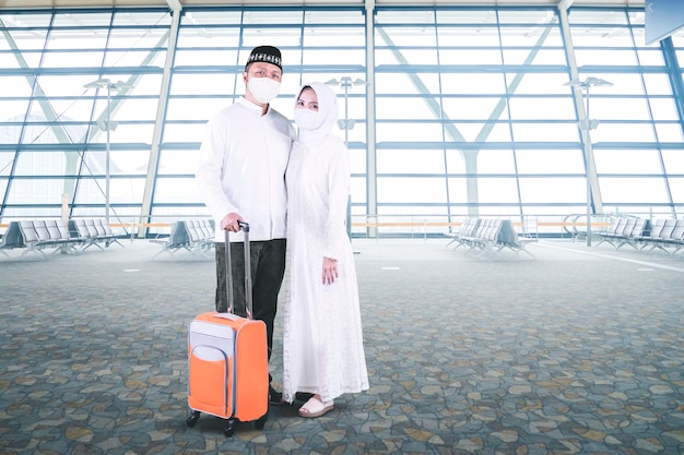 얼굴에 마스크를 쓴 무슬림 부부는 공항에서 짐을 들고 있다