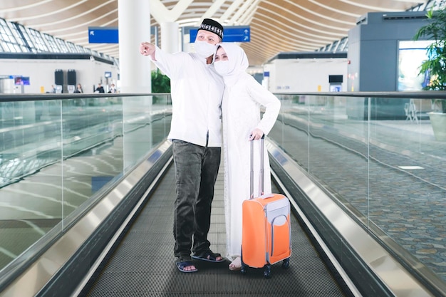 Muslim couple in mask pointing to flight information