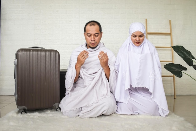 Muslim couple wearing white ihram and praying before going for umrah and hajj